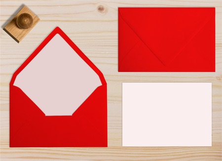 Set of red envelopes, with rubber stamp and card. Collection on light wooden background.
