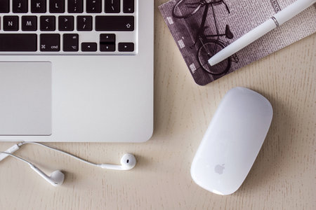 Laptop on wood table, earpods and mouse. Cozy workplace.のeditorial素材