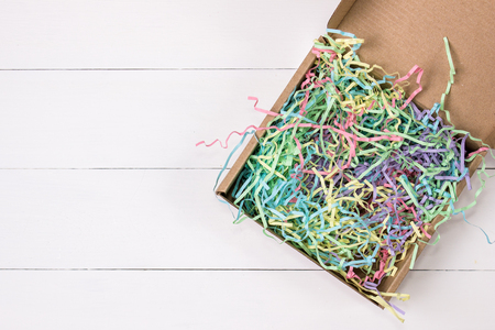 Opened gift mailing shipping cardboard box with colorful crinkle tissue inside. Top view.の写真素材