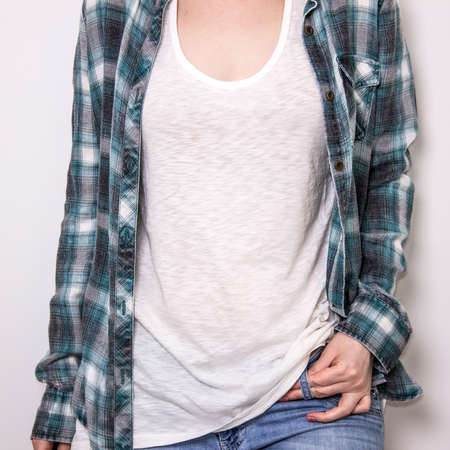 Cropped image of young hipster girl wearing blank white t-shirt under the plaid shirt, and blue jeans, mockup.の写真素材