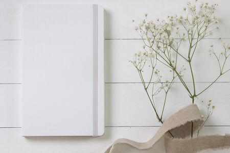 Mock-up of a white notebook, diary. Styled photo with flowers on the light boards