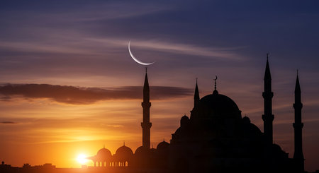 Silhouette of mosque and crescent moon at sunset. Ramadan Kareem backgroundの素材