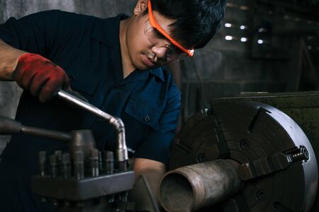 Asian mechanical engineer operating industrial lathe machine - Millennial internship boy training on manufacturing fabrication equipment - Diverse skilled hispanic immigrant factory worker in workshopの写真素材