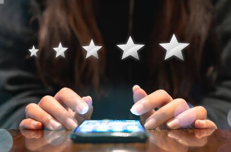 Woman filling out 5 star silver customer service feedback survey by email on smartphone device after...