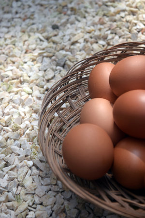 Eggs in a wicker basket on pebbles backgroundの写真素材