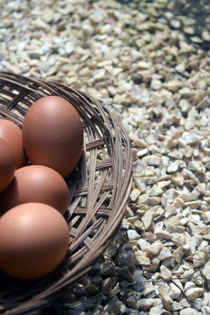 Eggs in a wicker basket on a background of pebblesの写真素材