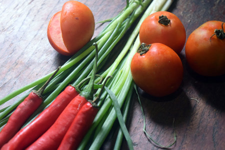 Tomatoes and chives on wooden table. Vegetables background.の写真素材