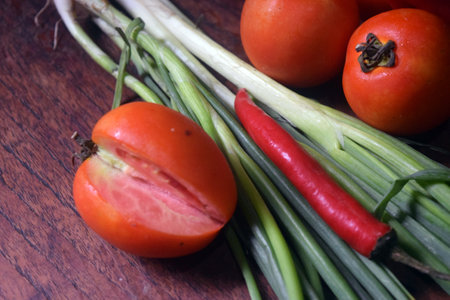 vegetables on wooden table, closeup of tomato and onionの写真素材
