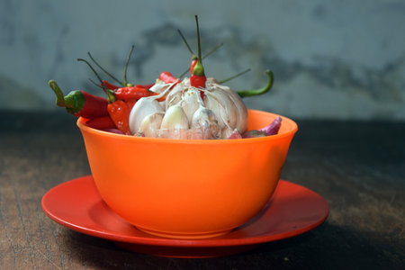 chilli and garlic in orange bowl on wooden table with copy spaceの写真素材
