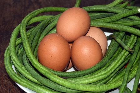 Fresh green beans and eggs on a white plate on a wooden tableの写真素材