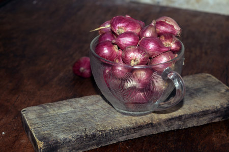Red onions in a glass cup on a wooden background. Selective focus.の写真素材
