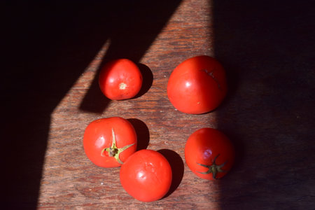 Tomatoes on the wooden table with shadow from the sun. Top view.の写真素材
