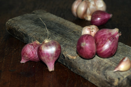 Red onions on a wooden cutting board on a dark background close-upの写真素材