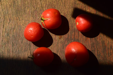 cherry tomatoes on wooden background with sunlight and shadow, top viewの写真素材