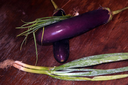 Purple eggplant and green onion on wooden table. Close up.の写真素材