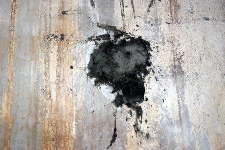 Old rusty sheet of metal with a black stain. Abstract background for design.の写真素材
