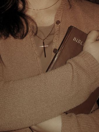 Woman with cross pendant holding the Bible to the chest.の写真素材
