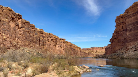 Scenic view of the Colorado River flowing through Marble Canyon in Arizona on a sunny day with blue skies. The canyon has steep red rock cliffs on either side. Taken at river level - USAの写真素材