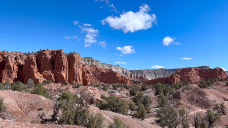 Panoramic view of the red rock formations and desert landscape of Kodachrome Basin State Park in Utah, USA. The blue sky provides a beautiful contrast to the red rocks and green vegetation.の写真素材