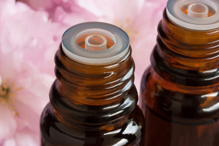 Two bottles of essential oil with pink blossoms in the backgroundの写真素材