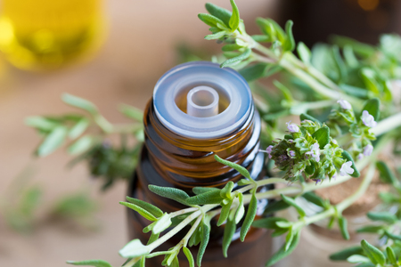 A bottle of thyme essential oil with fresh thyme leavesの写真素材