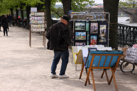 PRAGUE, CZECH REPUBLIC - APRIL 15, 2017: Unidentified man sellling his paintings on the riverbankのeditorial素材