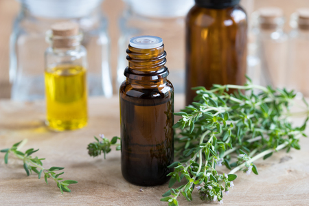 A bottle of thyme essential oil with fresh thyme twigsの写真素材