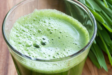 Green barley grass shot in a glass, with blades of young barley in the backgroundの写真素材