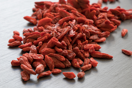 A pile of dried goji berries on a stone background.の写真素材