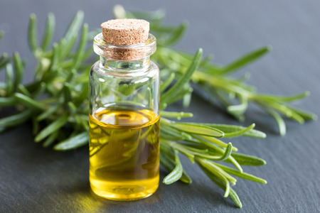 A bottle of essential oil with fresh rosemary twigs on a dark backgroundの写真素材