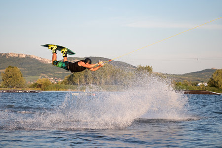 PASOHLAVKY, CZECH REPUBLIC - JUNE 24, 2017: Rider wakeboarding in the cable wake park Wake Merkur in South Moravia in front of the Palava mountainsのeditorial素材