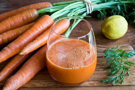 Carrot juice with fresh carrots on a wooden backgroundの写真素材
