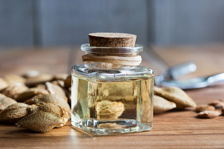 A bottle of apricot kernel oil with apricot kernels on a wooden backgroundの写真素材