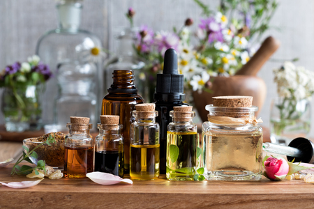 Selection of essential oils, with herbs and flowers in the backgroundの写真素材