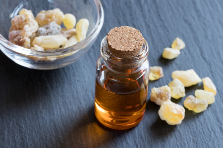A bottle of frankincense essential oil with frankincense resin crystals in the backgroundの写真素材