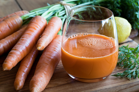 Carrot juice with fresh carrots and lemon on a wooden backgroundの写真素材