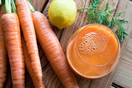 Carrot juice with fresh carrots and lemon on a wooden backgroundの写真素材