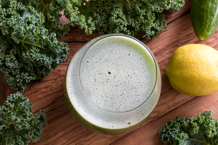 Vegetable juice with kale, cucumber, and lemon on a wooden backgroundの写真素材