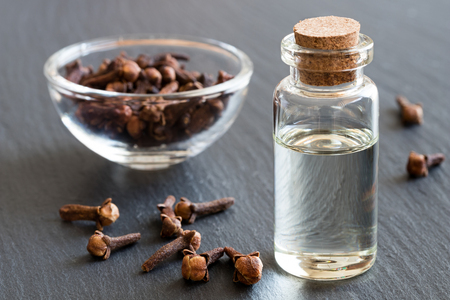 A bottle of clove essential oil with dried cloves in the backgroundの写真素材