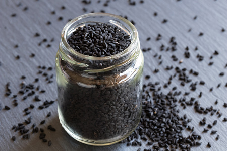 Black cumin seeds in a glass jar on a dark backgroundの写真素材