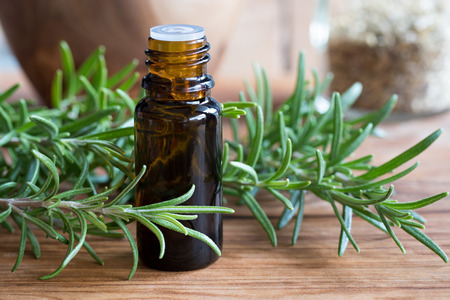 A dark bottle of rosemary essential oil with fresh rosemary twigsの写真素材