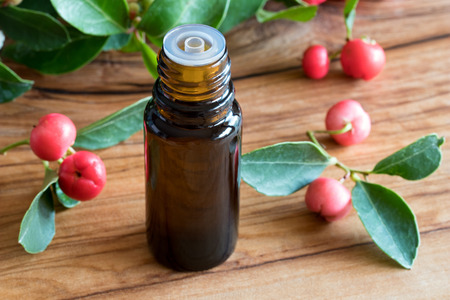 A bottle of wintergreen essential oil on a wooden table with wintergreen twigs in the backgroundの写真素材