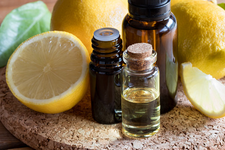 Bottles of lemon essential oil with fresh lemons in the backgroundの写真素材