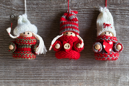 Christmas and winter background with copy space - three cute figures in warm hats and sweaters hanging over a wooden backgroundの写真素材
