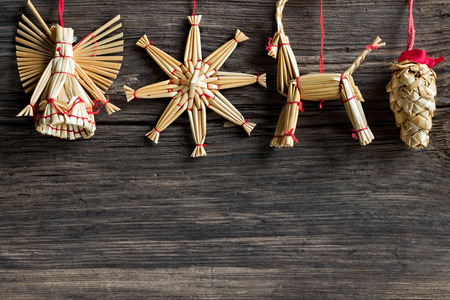 Simple Christmas background with copy space - straw ornaments hanging over a wooden backgroundの写真素材