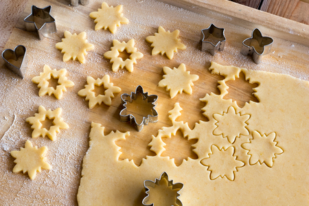 Cutting out star shapes from rolled out dough to prepare traditional Linzer Christmas cookiesの写真素材