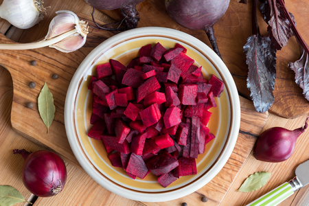 Sliced red beets on a plate, with fresh beets, onions, garlic and spices in the background - preparation of fermented beets. Top  view.の写真素材