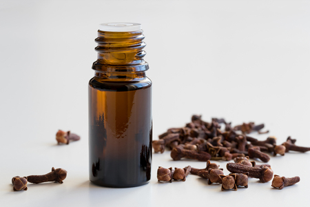 A bottle of clove essential oil with dried cloves on a white backgroundの写真素材