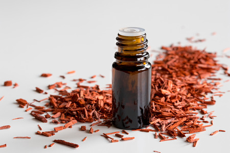 A bottle of sandalwood essential oil with sandalwood on a white backgroundの写真素材