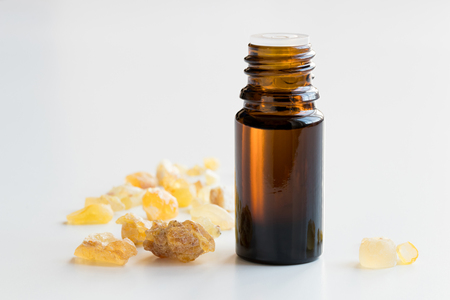 A dark bottle of frankincense essential oil with frankincense resin on a white backgroundの写真素材